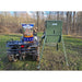 Green American Feeder AF300 Wildlife Feeder on tripod legs next to an ATV carrying a bag of deer feed in a wooded clearing