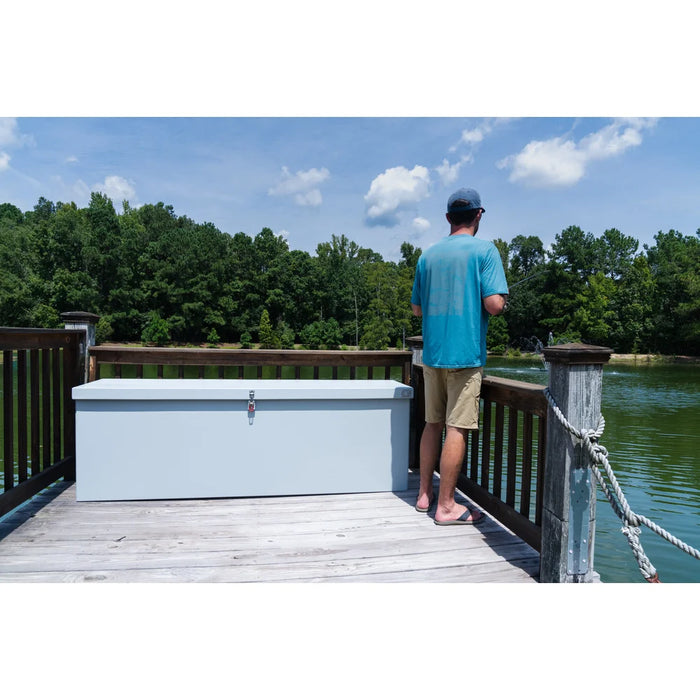 Man fishing beside the closed American Feeder DB-8020 Dock Box on a wooden dock overlooking a pond on a sunny day