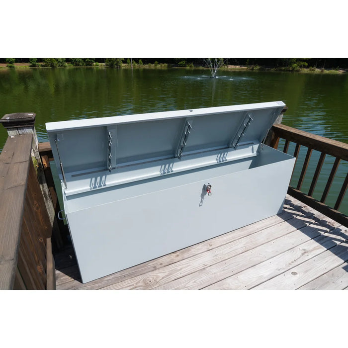 American Feeder DB-8020 Dock Box open on a wooden dock beside a pond, lid raised showing rod holder brackets and latch