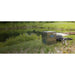 Kasco Home Series Diffused Aeration System stainless cabinet on grass by a pond with coiled weighted tubing