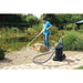 Man vacuuming a garden pond edge with the OASE PondoVac 4 pond and pool vacuum standing on the paved path nearby