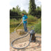 Man using the OASE PondoVac 4 wet vacuum cleaner to clean the edge of a natural garden pond with the extension pipe