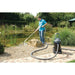 Man cleaning a garden pond with the OASE PondoVac 4 pond and pool vacuum, the canister sitting on paving with hose extended