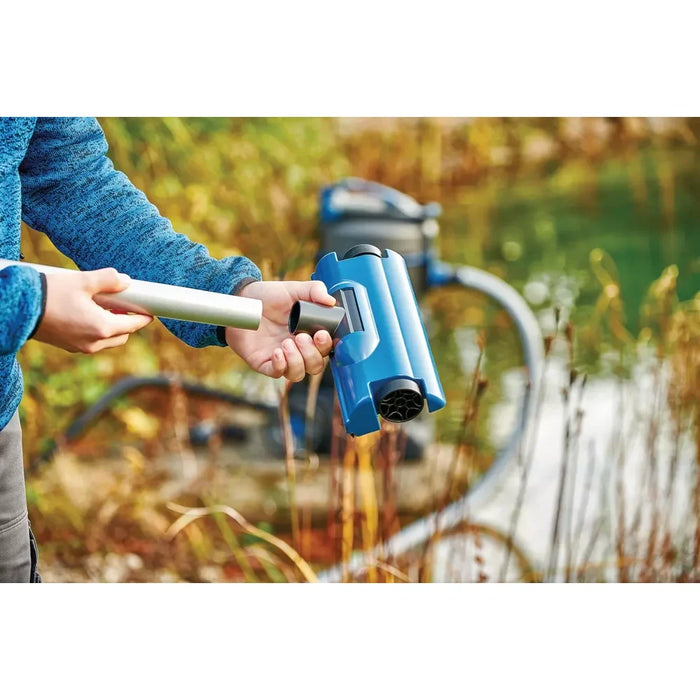 Hands attaching the blue roller surface brush nozzle to the Oase PondoVac 5 Pond Vacuum pole outdoors near water