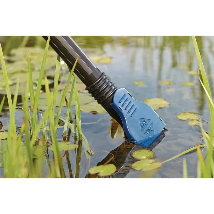 Oase PondoVac Classic pond vac flat nozzle drawing water and debris from a pond surface surrounded by lily pads and reeds