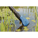 Oase PondoVac Classic pond vac flat nozzle drawing water and debris from a pond surface surrounded by lily pads and reeds