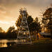 Outdoor Water Solutions 4 Leg Windmill Pond Aerator tall galvanized tower on concrete footers beside a pond at sunset