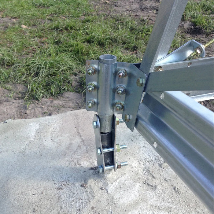Close-up of the Outdoor Water Solutions 4-Leg Steel Windmill Aerator tower hinge and bolted base bracket on concrete