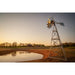 Side view of the Outdoor Water Solutions 3 Leg Windmill Water Aerator by a farm pond at sunset