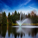 scott_aerator_skyward_pond_fountain_with_green_led_light_kit_in_water_with_trees_in_background